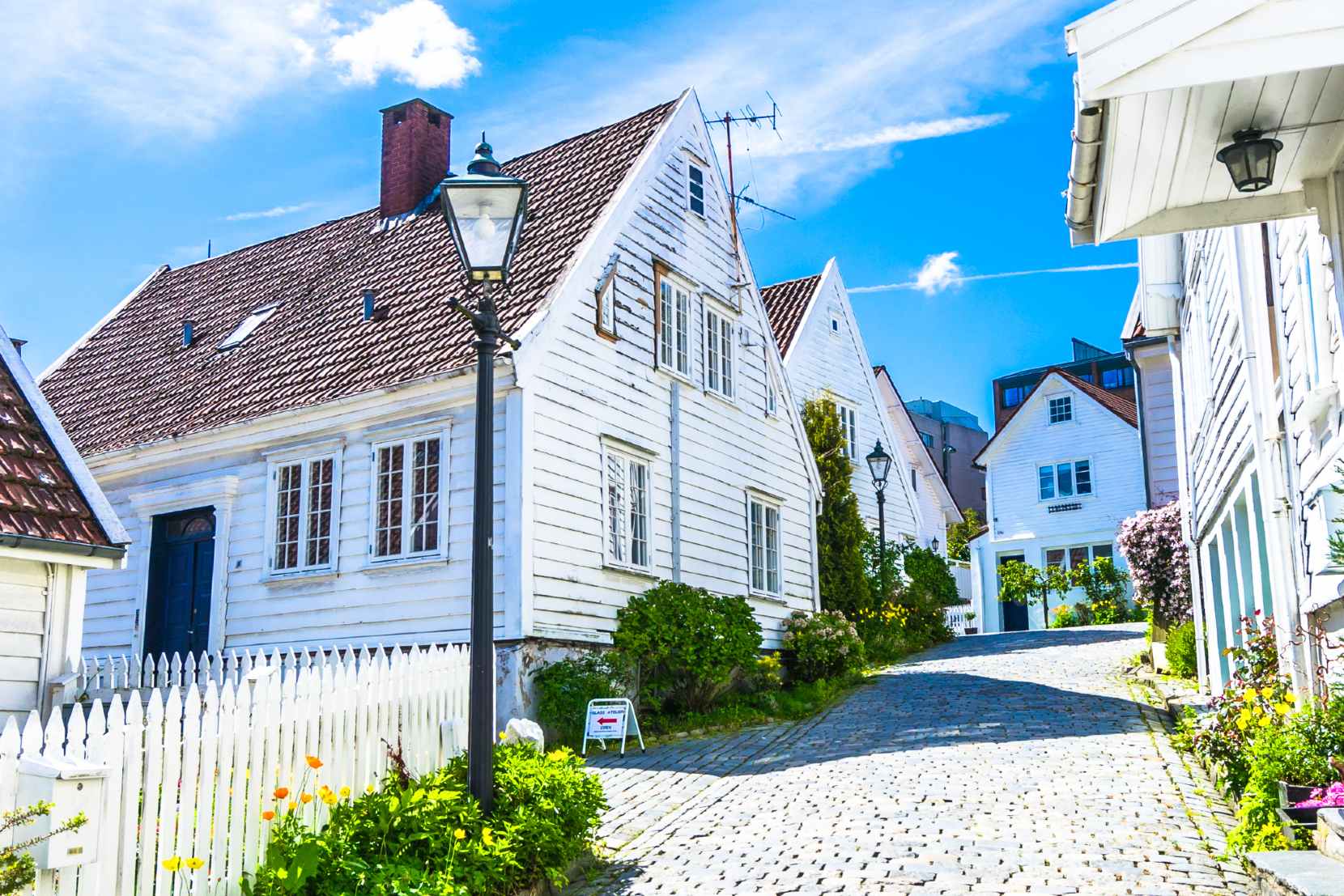 Idyllic street in Norway with white houses and cobblestones in the summer